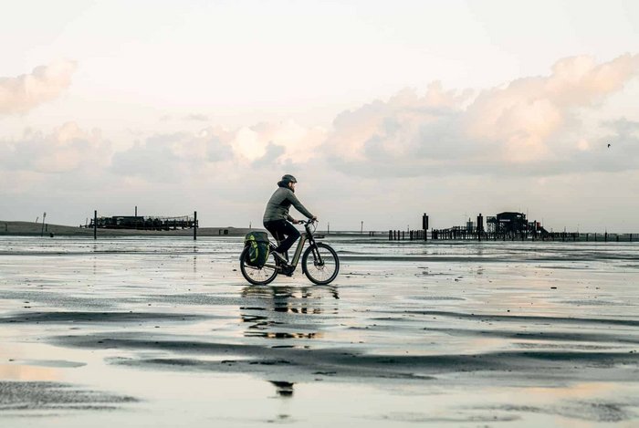 Victoria Person cycling at the seaside during low tide with water reflections