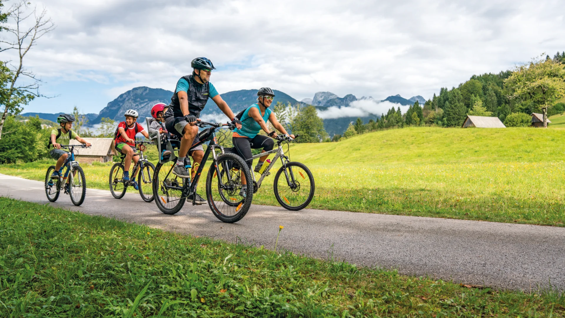 Familie fietst op landweg met bergen en velden