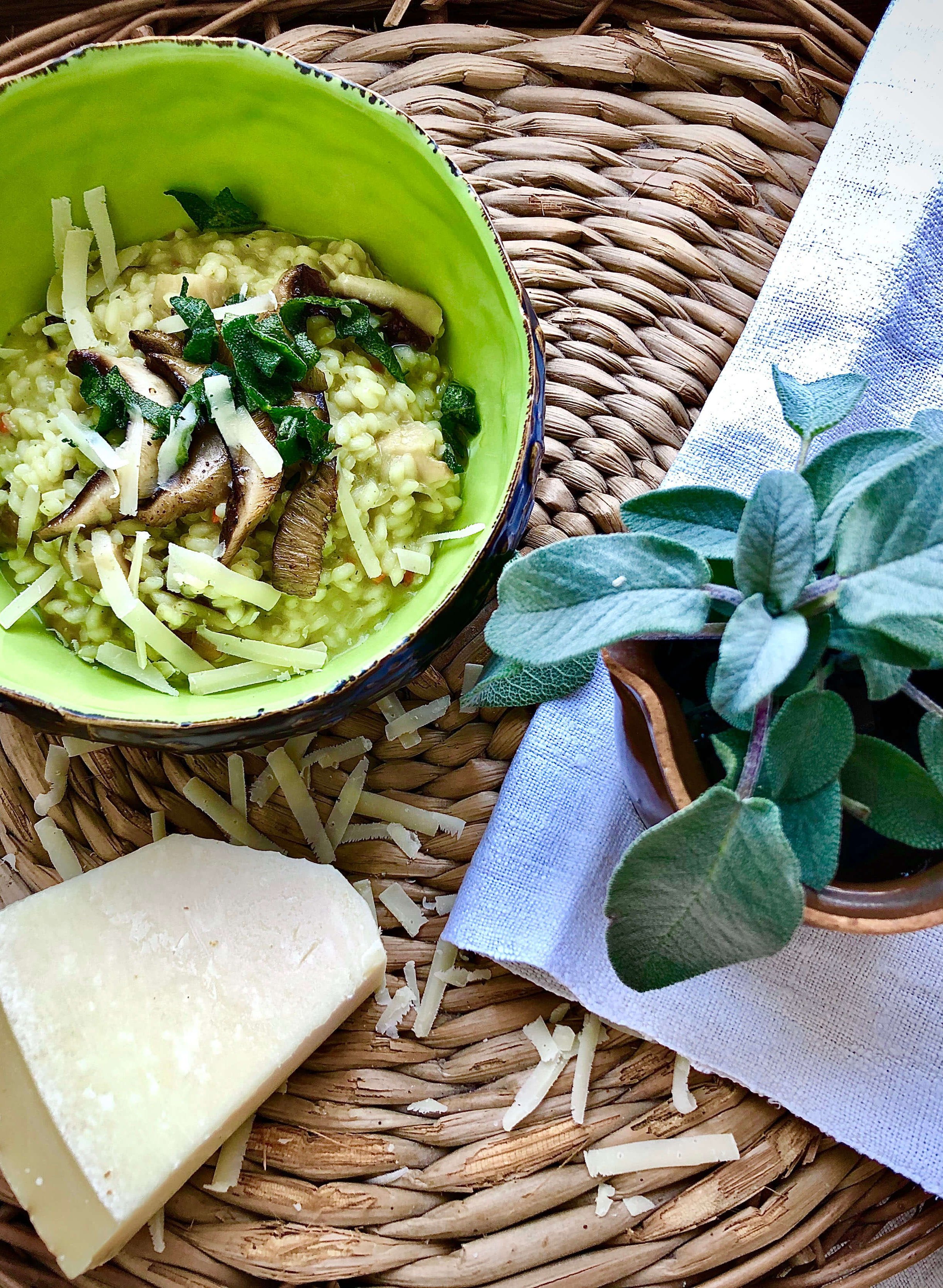 Green risotto with mushrooms, cheese, and fresh herbs in a green bowl