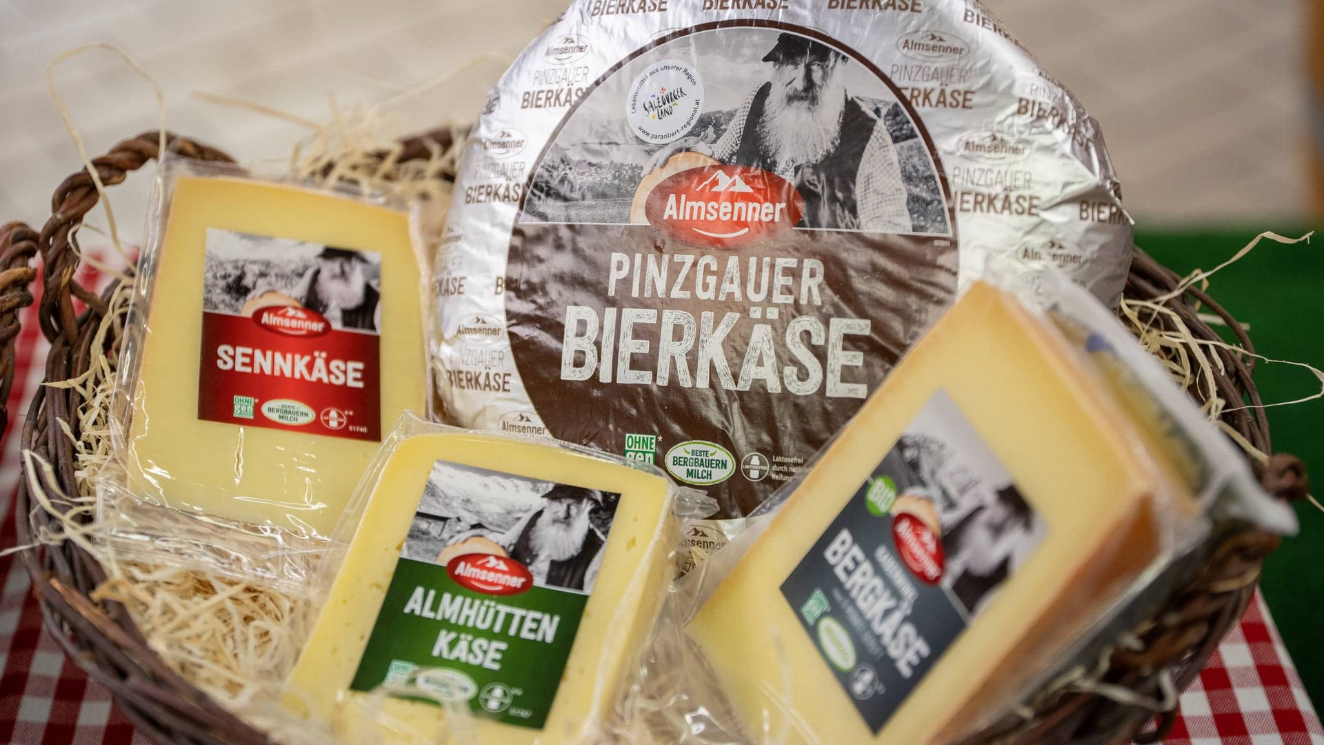 Various Austrian cheeses in a basket with straw on a red and white checkered cloth