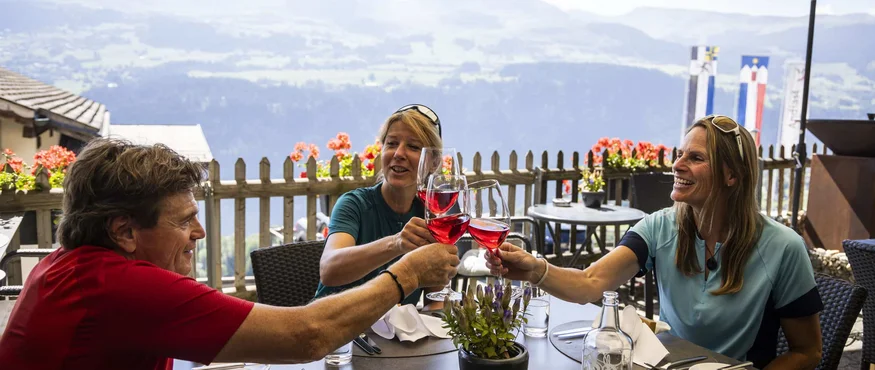 Vier Tage, vier Seiten der RheinWelten © Heiko Mandl Drei Personen stoßen mit Rotwein auf einer Terrasse mit Bergblick an