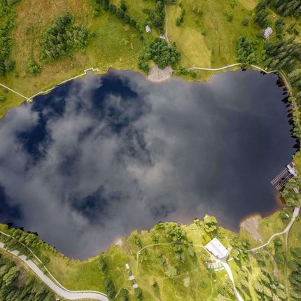 Aerial view of a lake surrounded by meadows and forests
