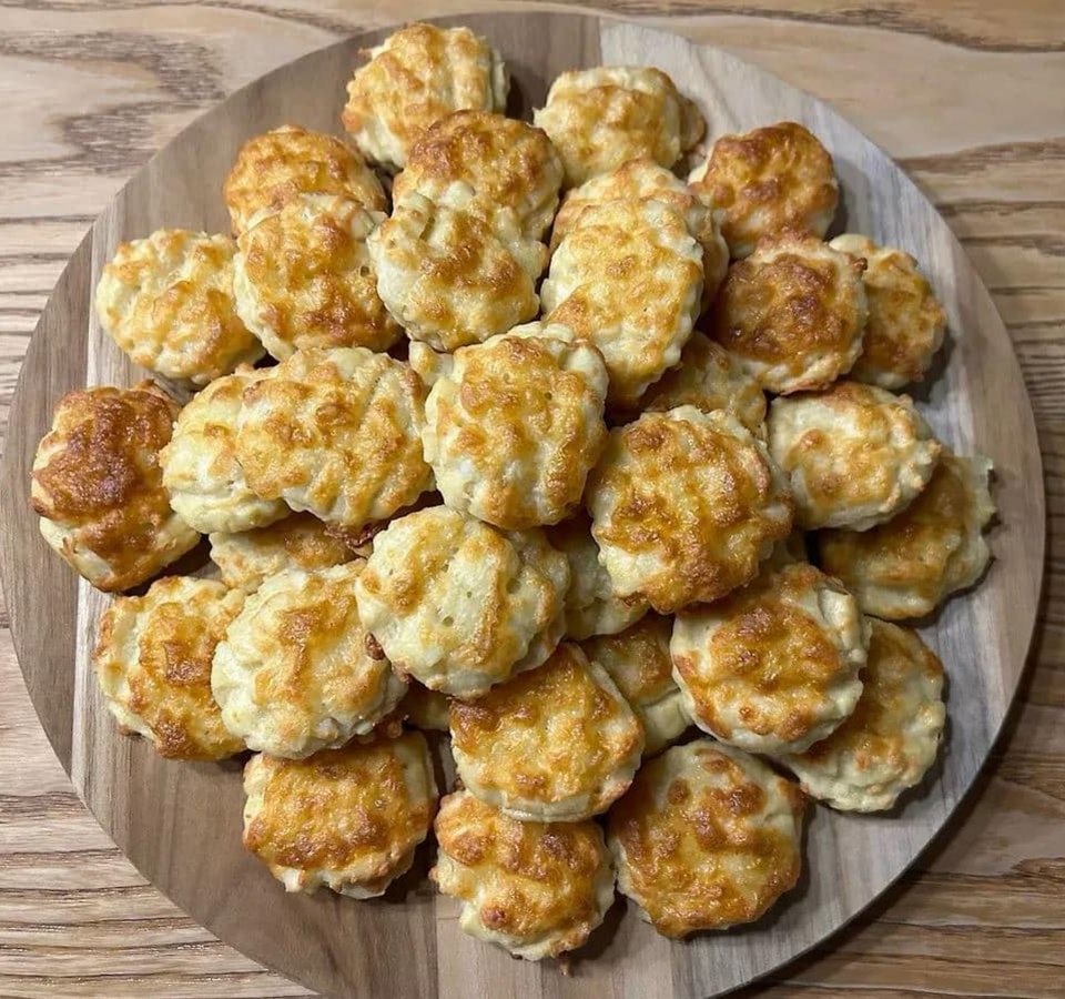 Plate of small baked cheese pastries on wooden surface