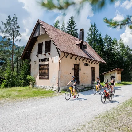 Familie fietst op een pad voor een oud huis in het bos