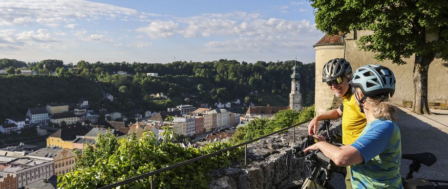 Two cyclists enjoying city view from a high stone wall