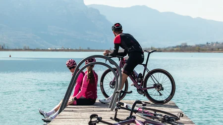 Kulinarisch unterwegs in Tramin © TV Kaltern am See - Felix Homann Drei Radfahrer auf einem Steg am See mit Bergen im Hintergrund