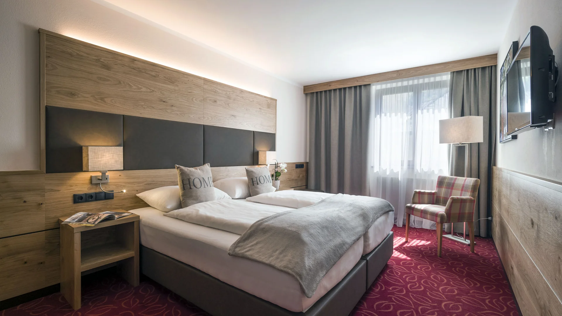 Hotel Andreas Hofer Kufstein **** © Hotel Andreas Hofer Kufstein Modernes Hotelzimmer mit Doppelbett, Sessel und Fernseher an der Wand