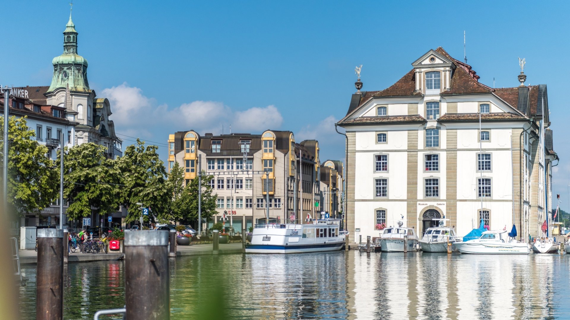 Boats at harbor with historic buildings under clear sky