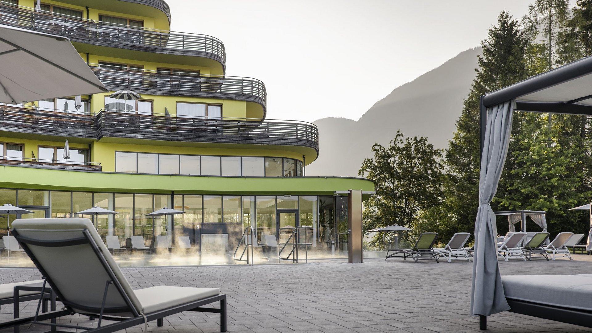 Hotel terrace with lounge chairs in front of modern building and mountain view