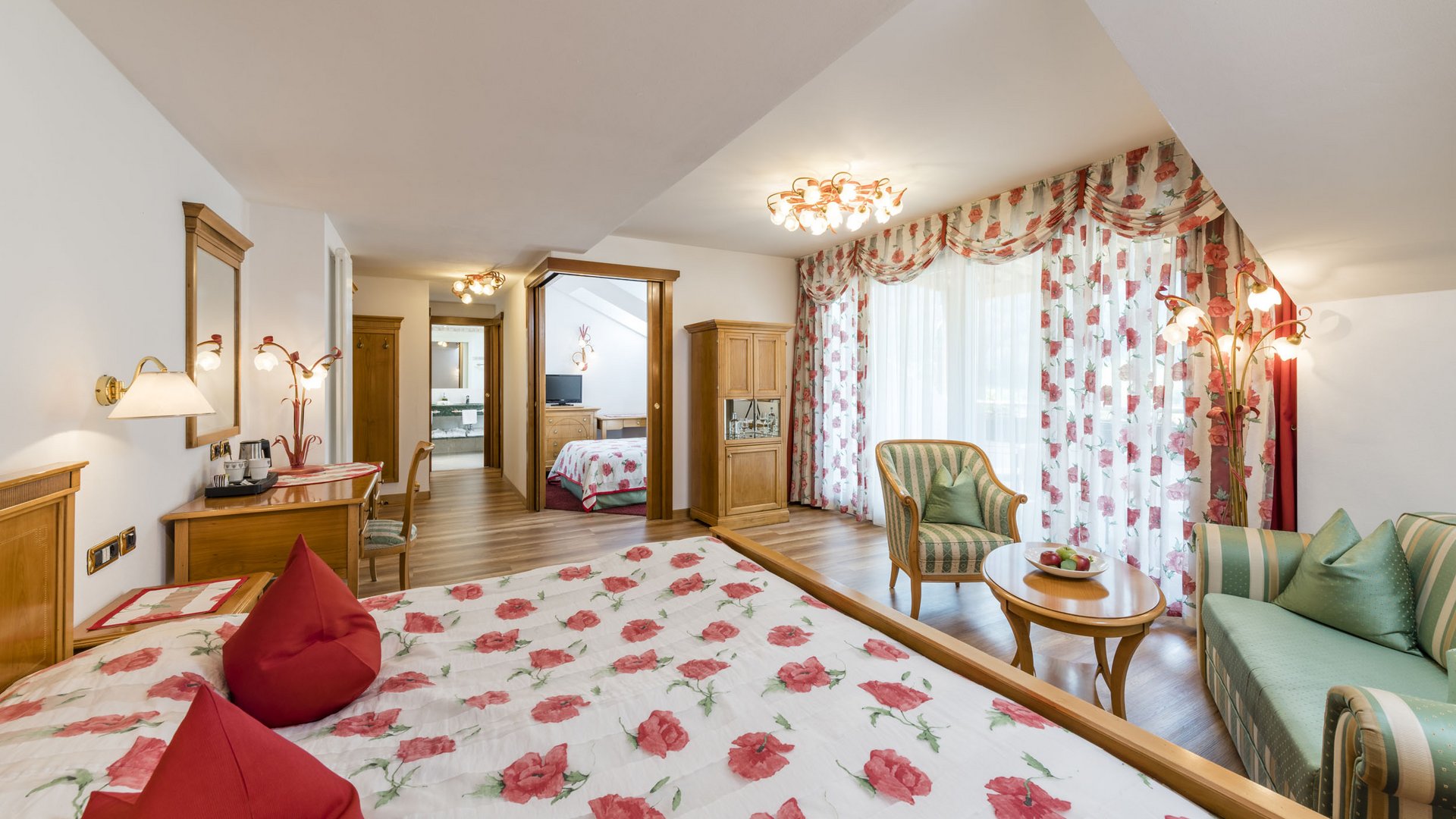 Bright hotel room with floral curtains and red flower bedspread
