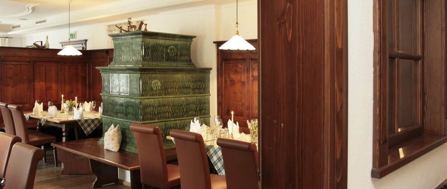 Traditional restaurant with green tiled stove and set dining tables