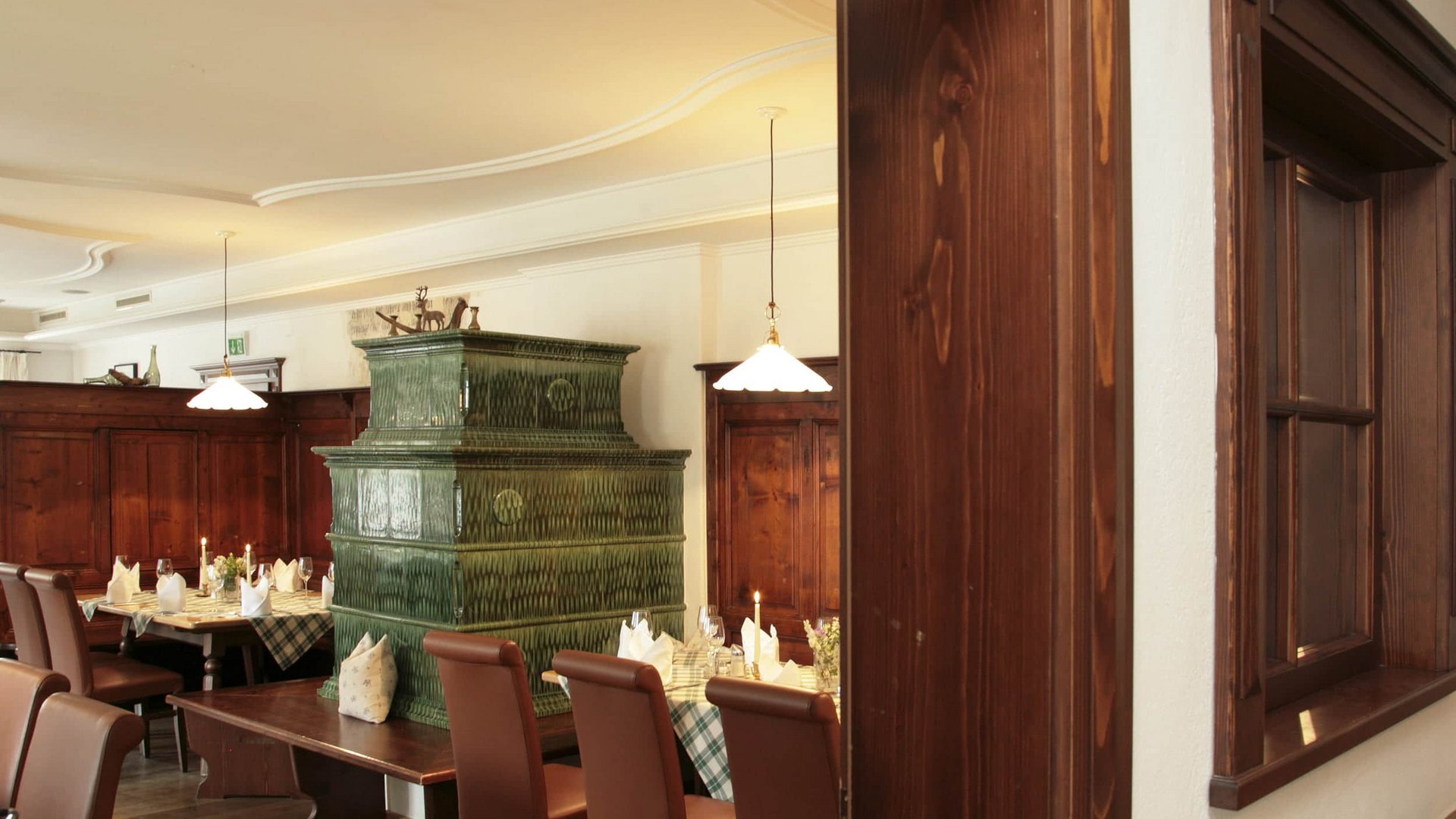 Traditional restaurant with green tiled stove and set dining tables