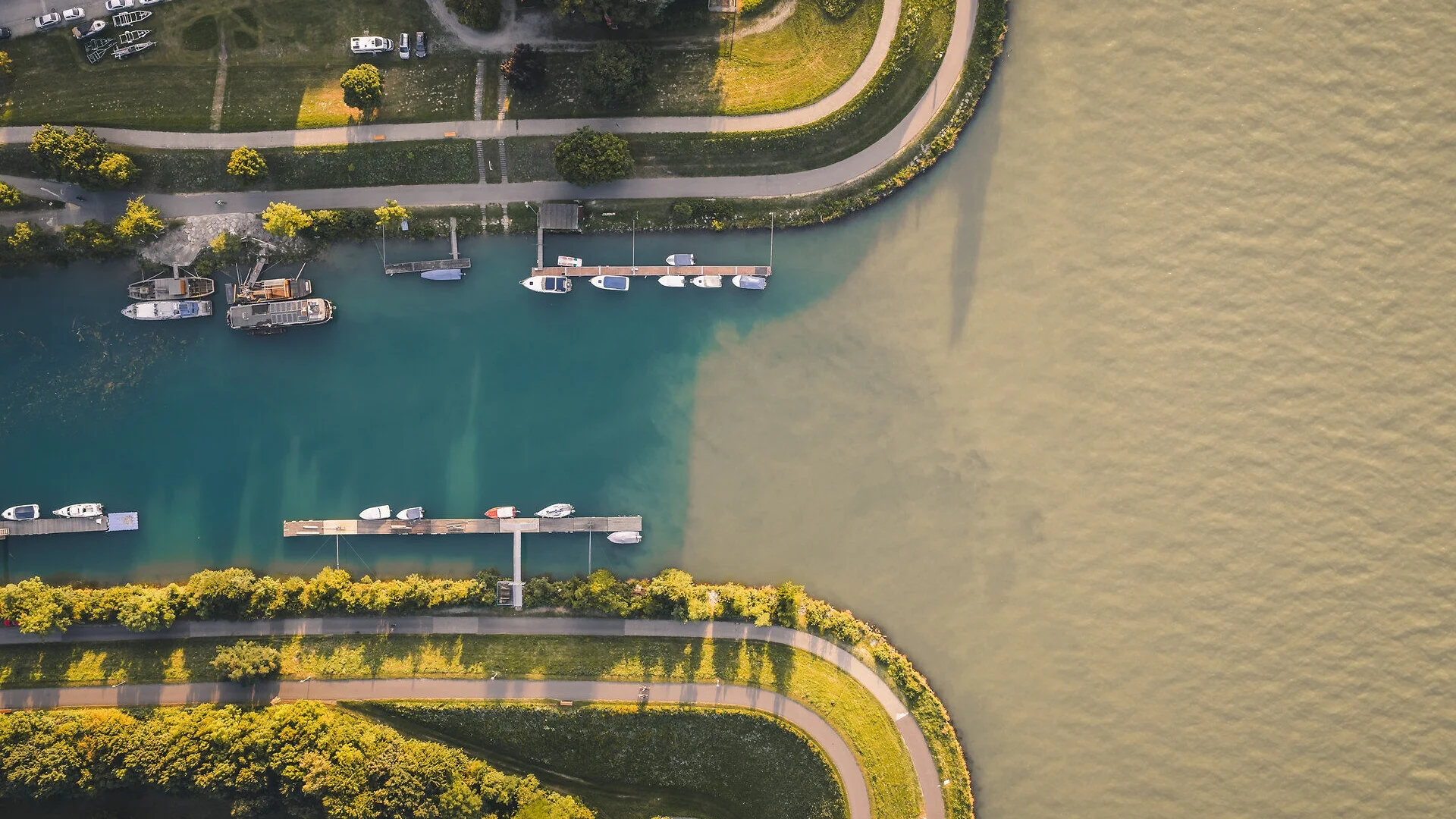 Tour-Detail Luftaufnahme einer grünen Uferpromenade mit Booten und Parkplätzen