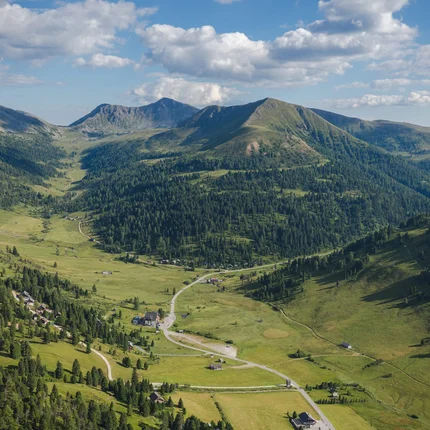 Uitzicht op een groen dal met bergen en een blauwe lucht met wolken