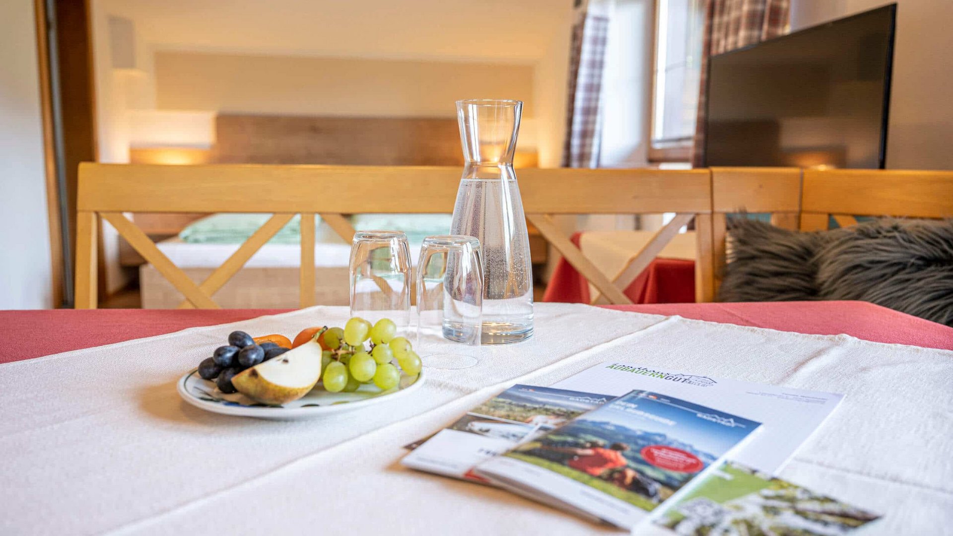 Table with water carafe, glasses, fruit plate, and brochures in cozy room
