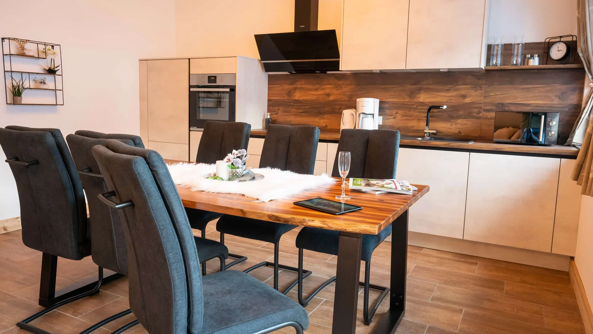 Modern dining area with wooden table and six black chairs in open kitchen