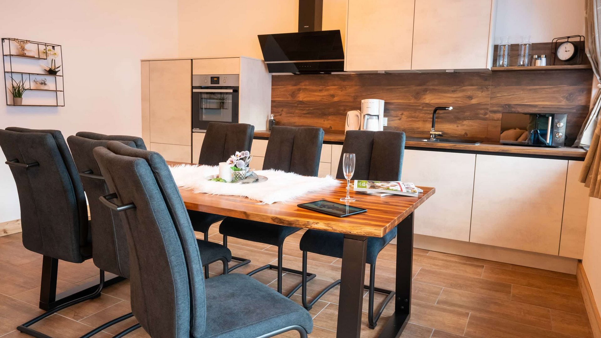 Modern dining area with wooden table and six black chairs in open kitchen