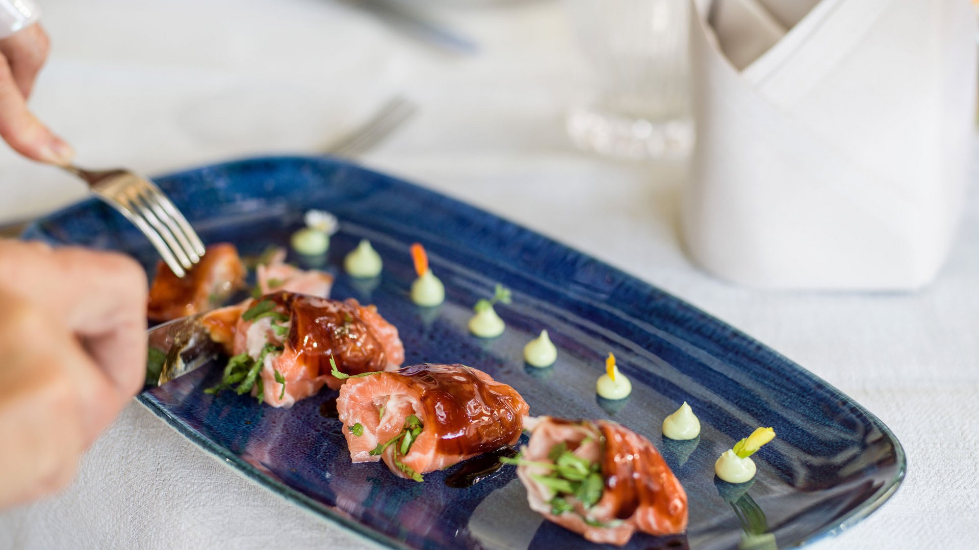 Salmon rolls with sauce arranged on blue plate