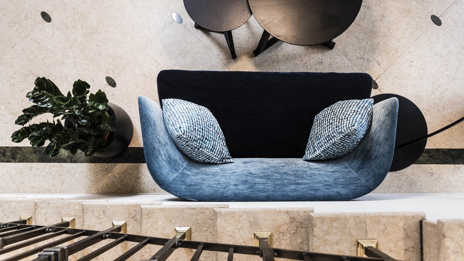 Modern seating area with blue armchair, black tables, and potted plant viewed from above