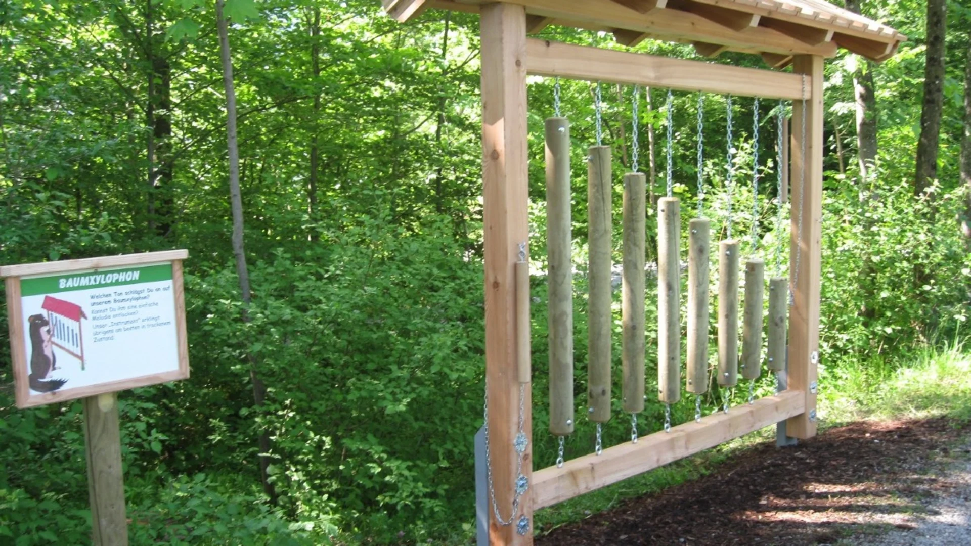 Buiten houten boomxylofoon met hangende houten buizen in bosrijke omgeving