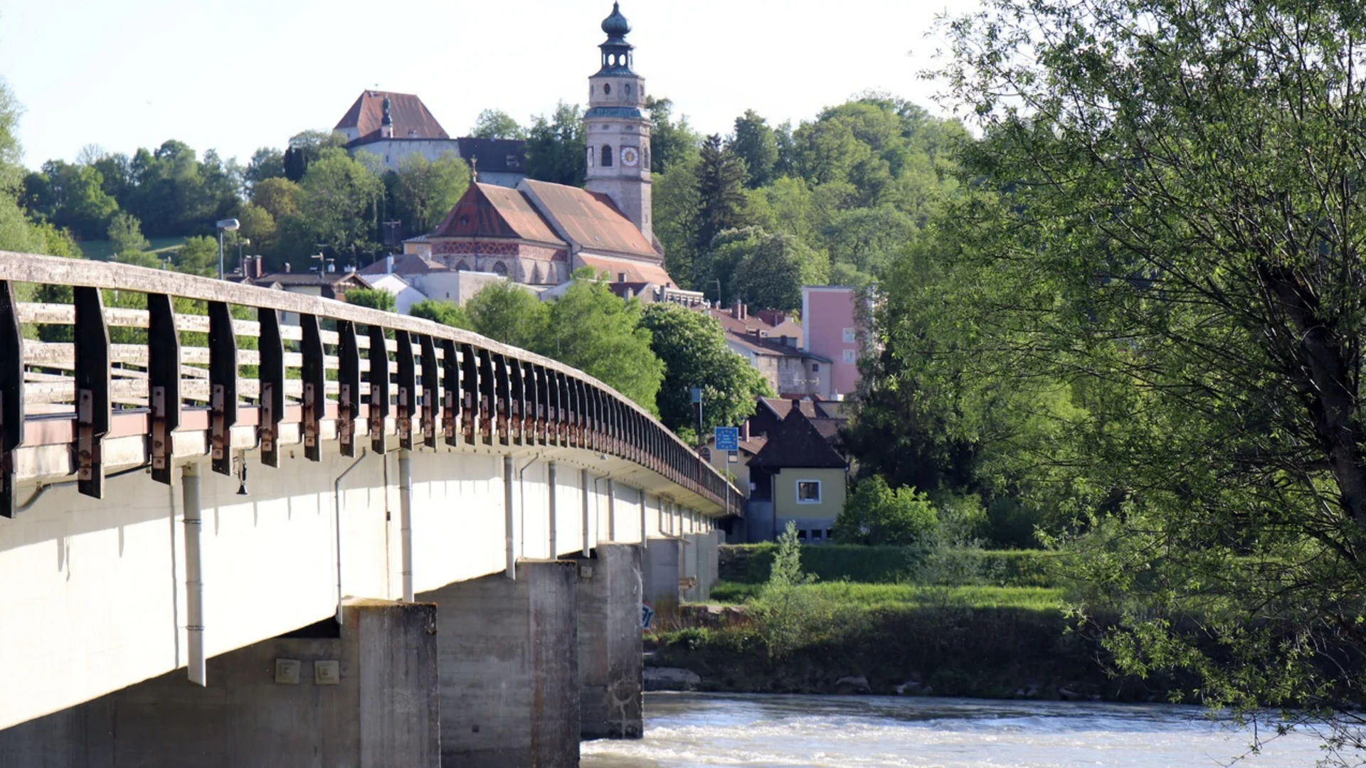 Brücke über Fluss mit Kirche und Gebäuden im grünen Tal