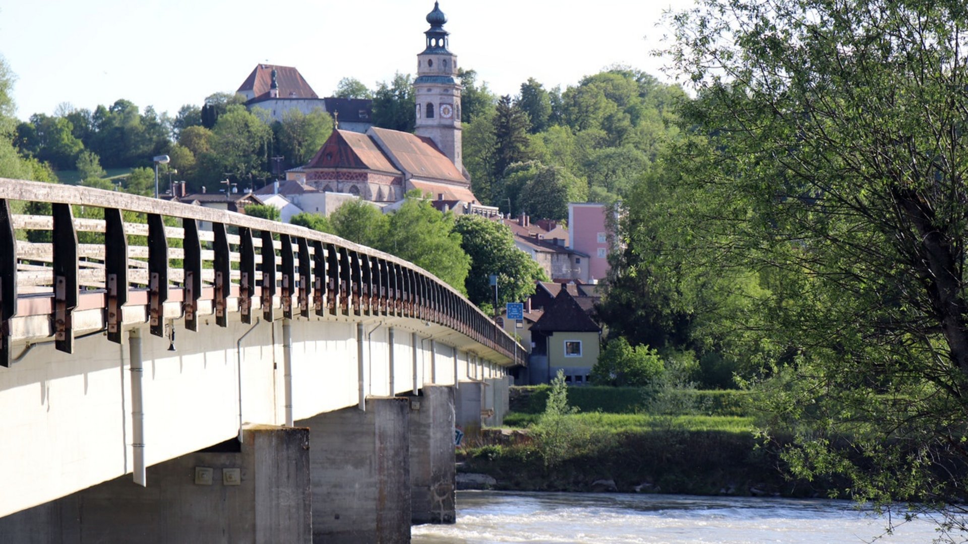 Bridge over river with church and buildings in a green valley