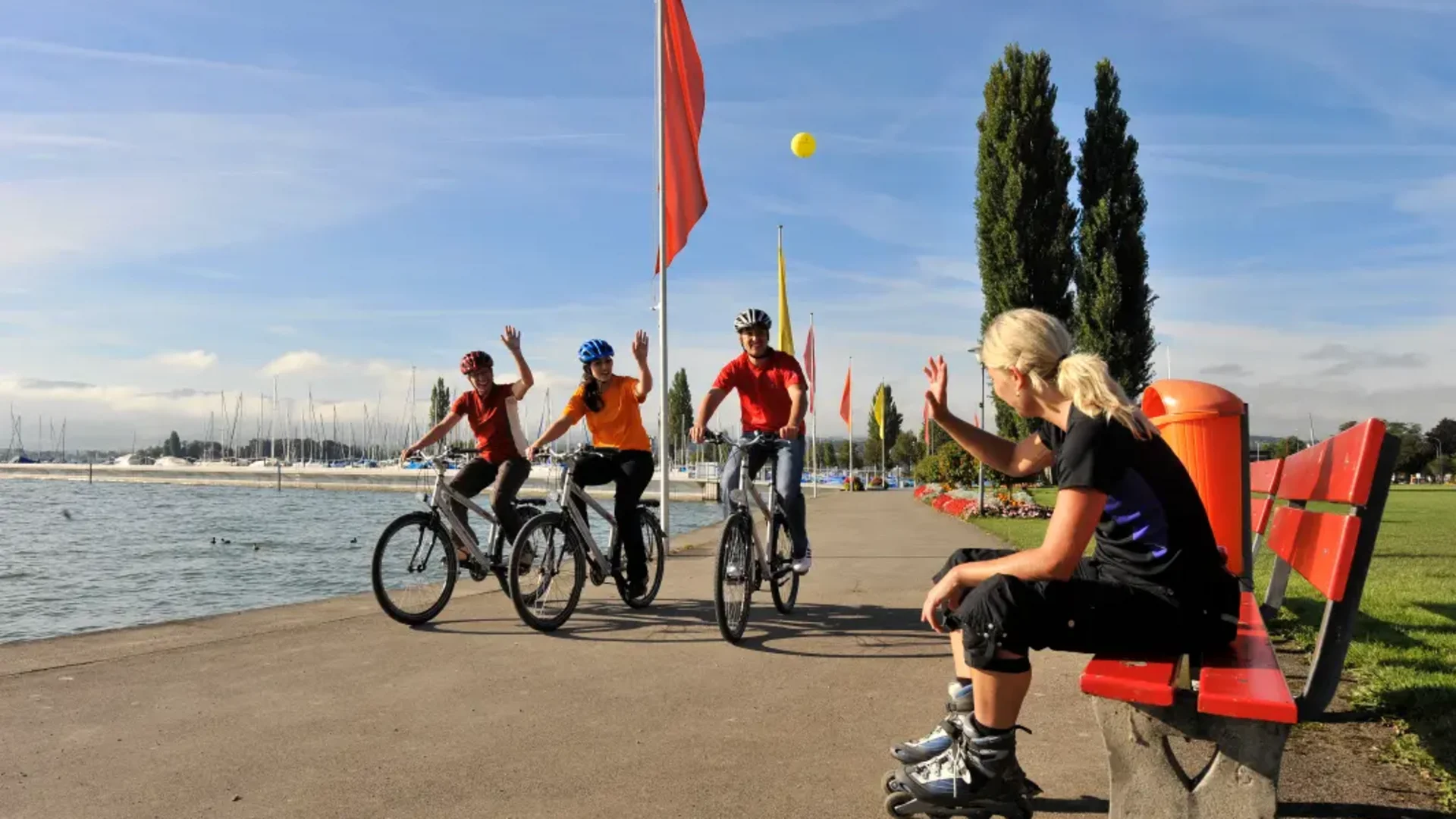 Vrouw op rolschaatsen groet drie fietsers aan het meer