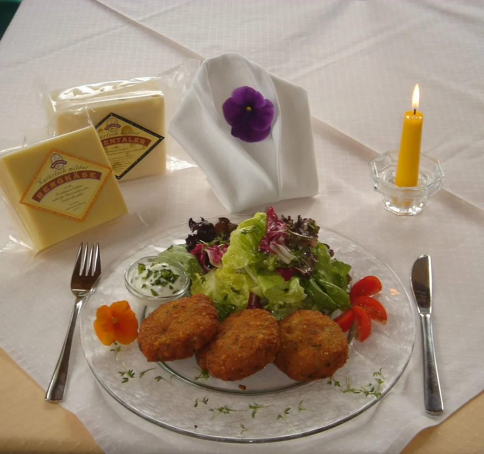 Bord met salade en drie gefrituurde kroketten, twee kaasblokken en een brandende kaars