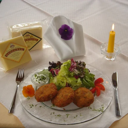 Bord met salade en drie gefrituurde kroketten, twee kaasblokken en een brandende kaars