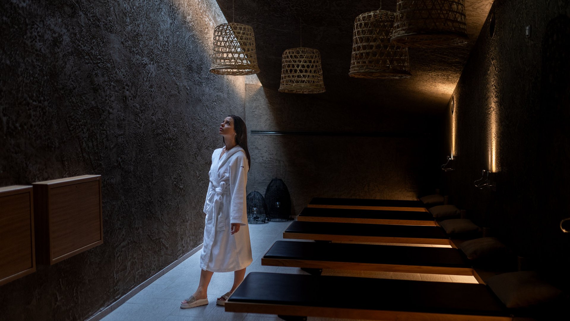 Woman in a bathrobe in a dark spa room with lounge chairs
