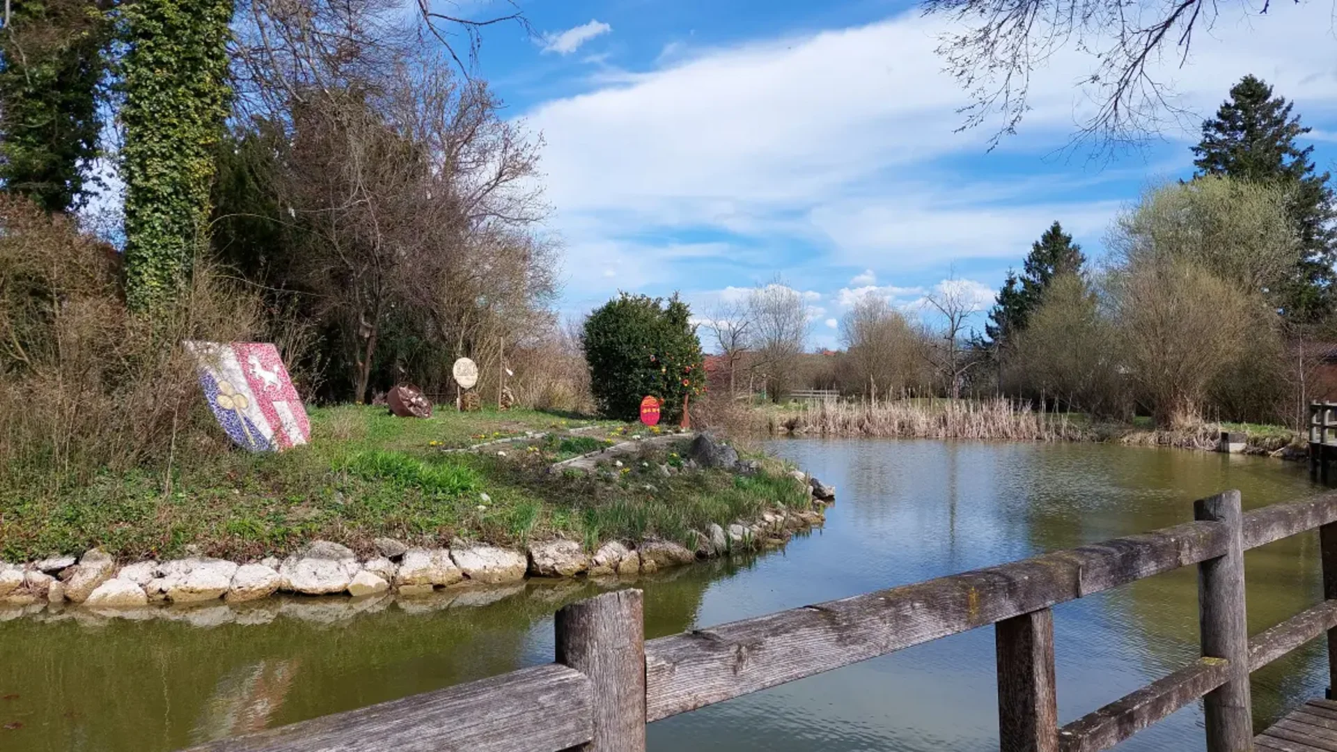 Fluss mit steiniger Uferbefestigung und bemalten Holzschildern am Rand