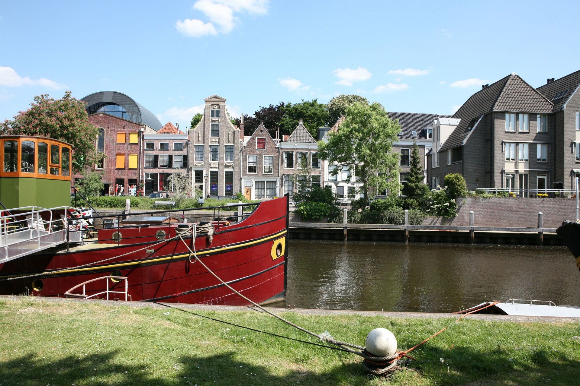 Red boat moored by the river with historic houses in the background