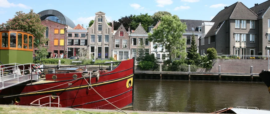 Red boat moored by the river with historic houses in the background