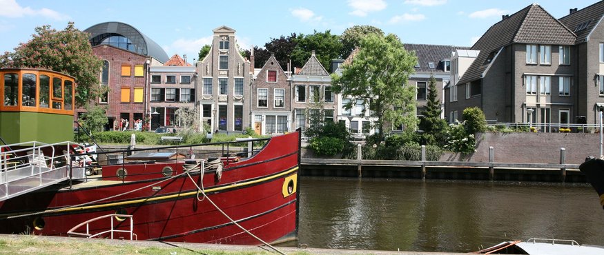 Red boat moored by the river with historic houses in the background