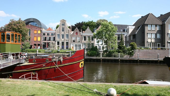 Red boat moored by the river with historic houses in the background
