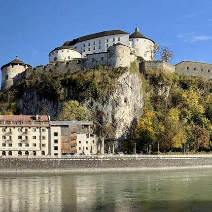 Burg auf einem Felsen über dem Fluss mit umliegenden Häusern und Bäumen