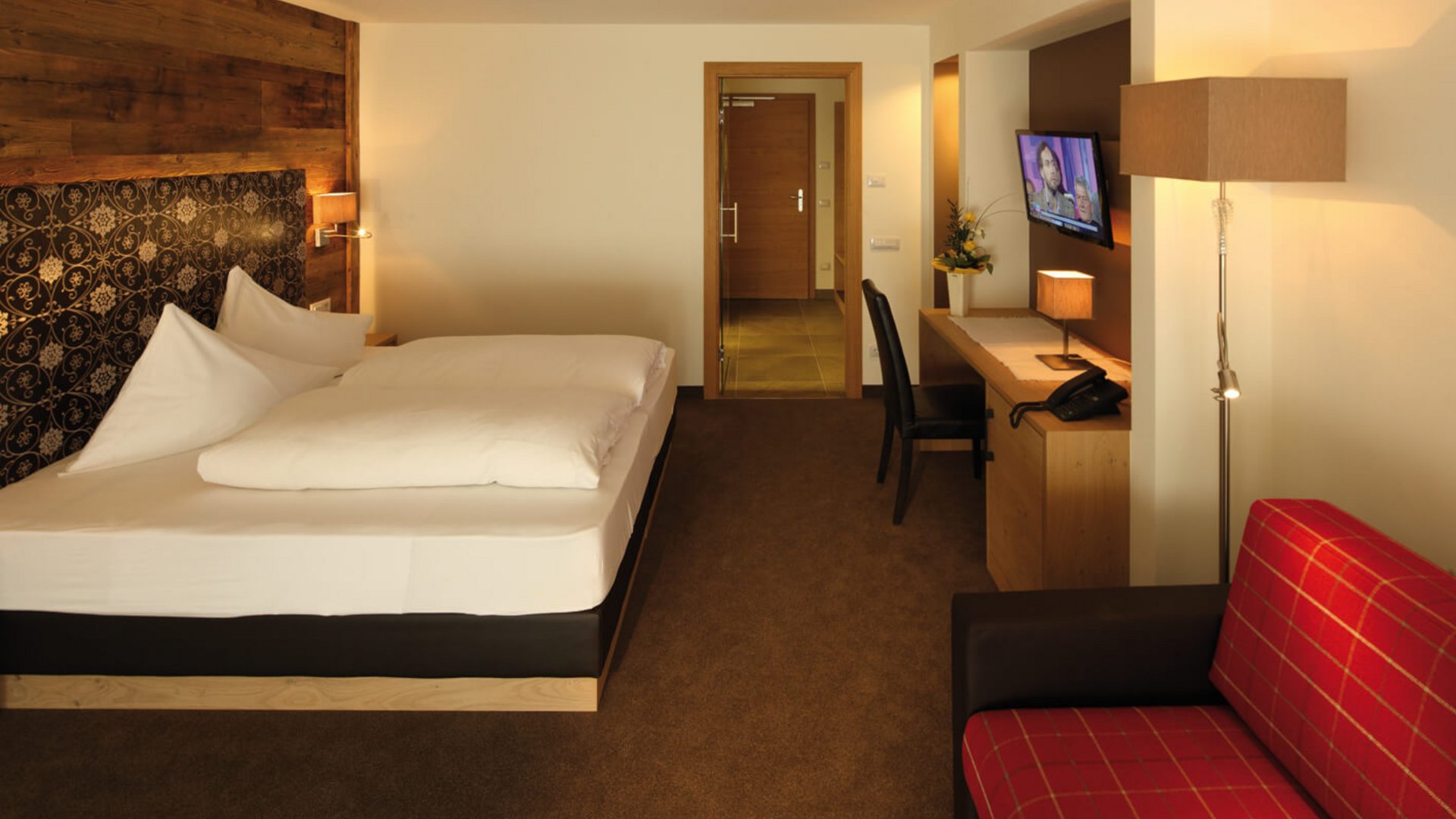 Modern hotel room with double bed, desk, and TV