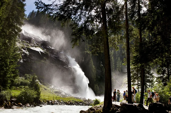 RadGENUSS im kleinen Juwel Maishofen © Krimmler Wasserfälle Touristen beobachten einen großen Wasserfall im Wald bei Sonnenschein