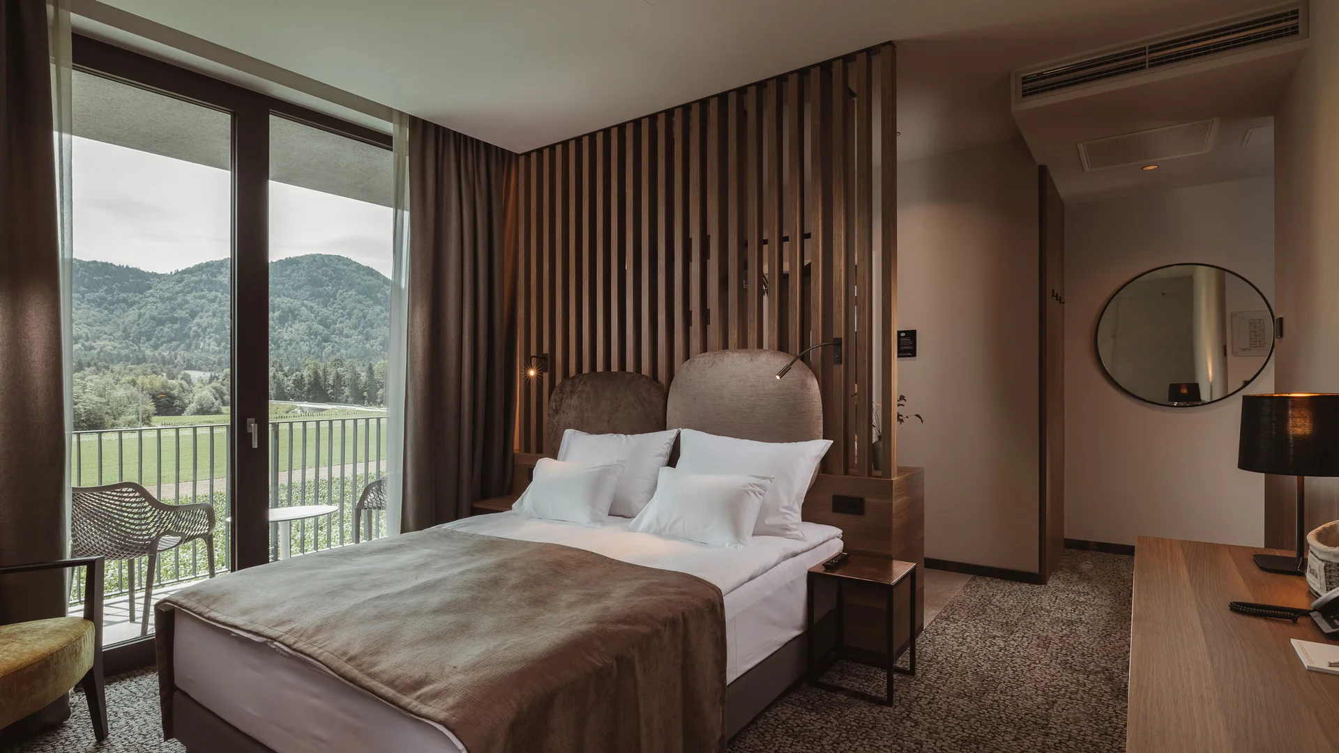 Moderne hotelkamer met tweepersoonsbed en balkon met uitzicht op bergen