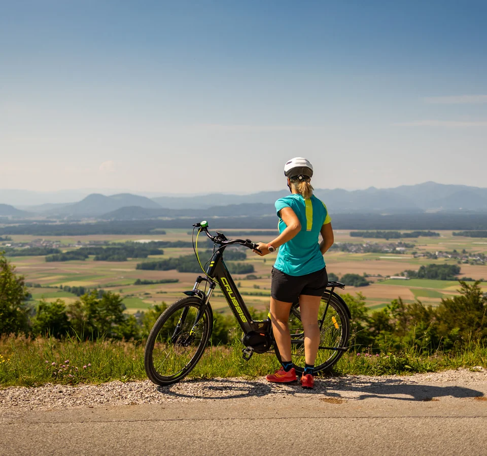 Frau mit Fahrrad auf Bergblick auf Tal und Berge bei klarem Himmel