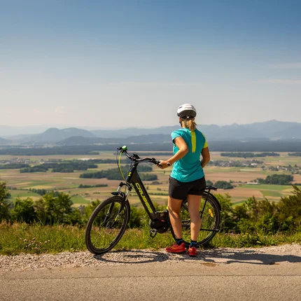 Frau mit Fahrrad auf Bergblick auf Tal und Berge bei klarem Himmel