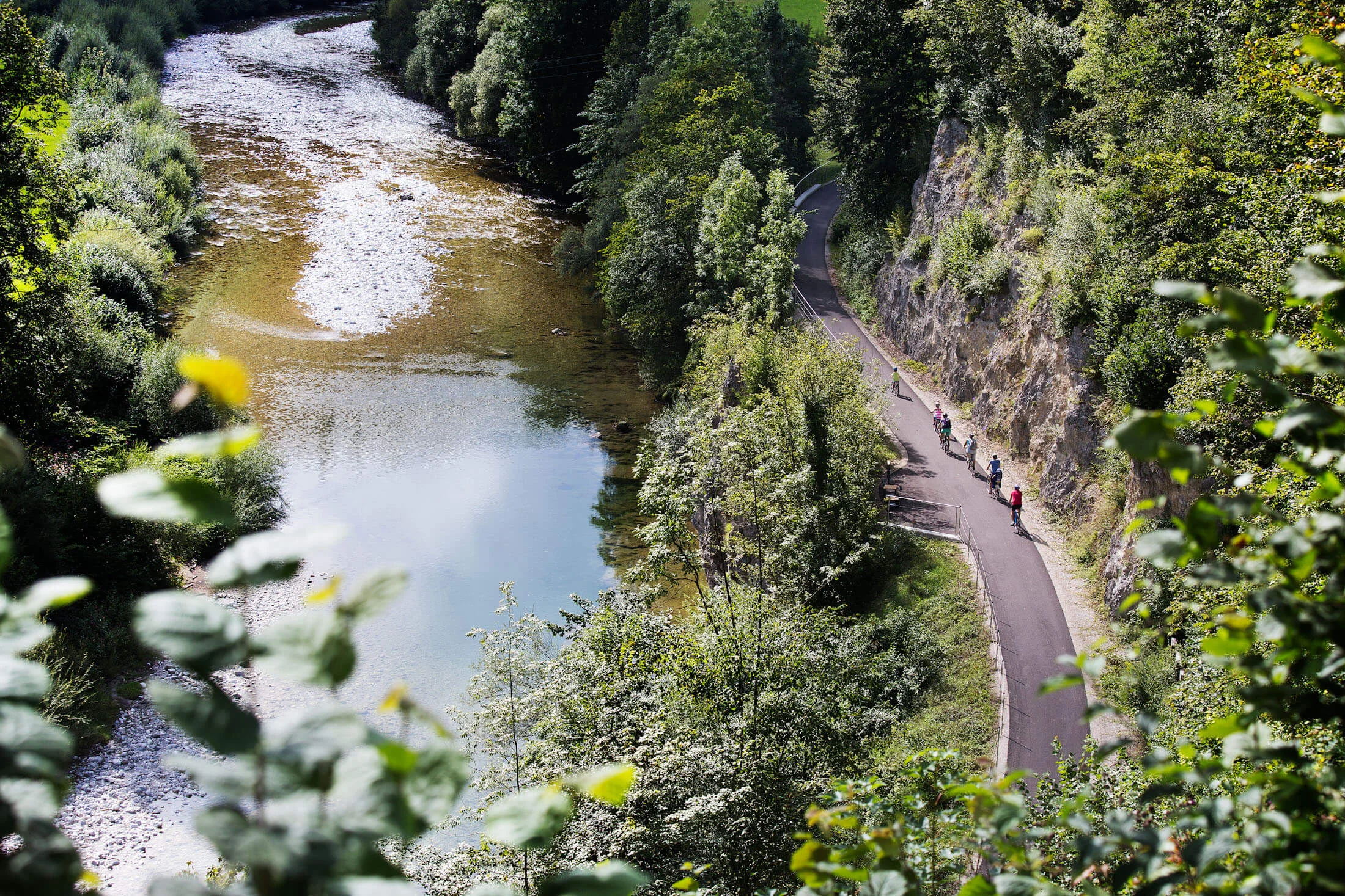 Fahrradfahrer auf einem Waldweg entlang eines Flusses