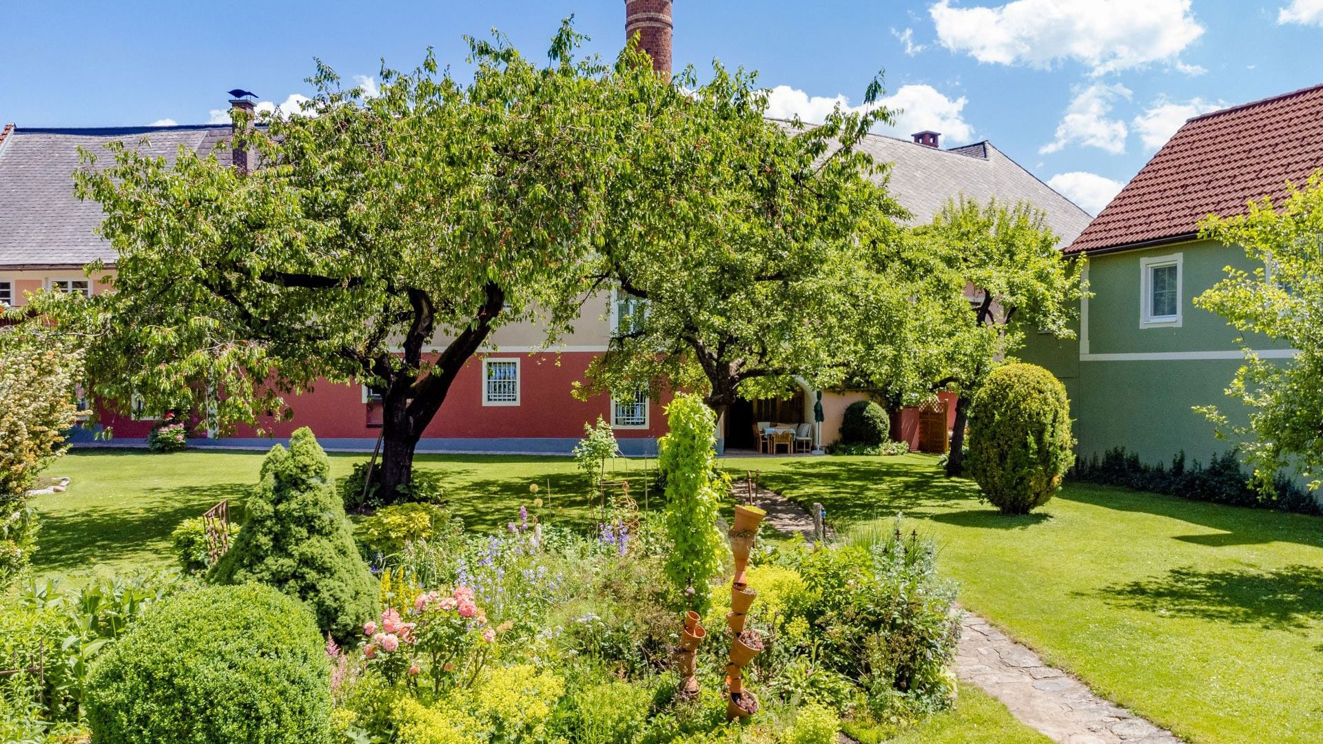 Flower garden with trees and houses under a sunny sky