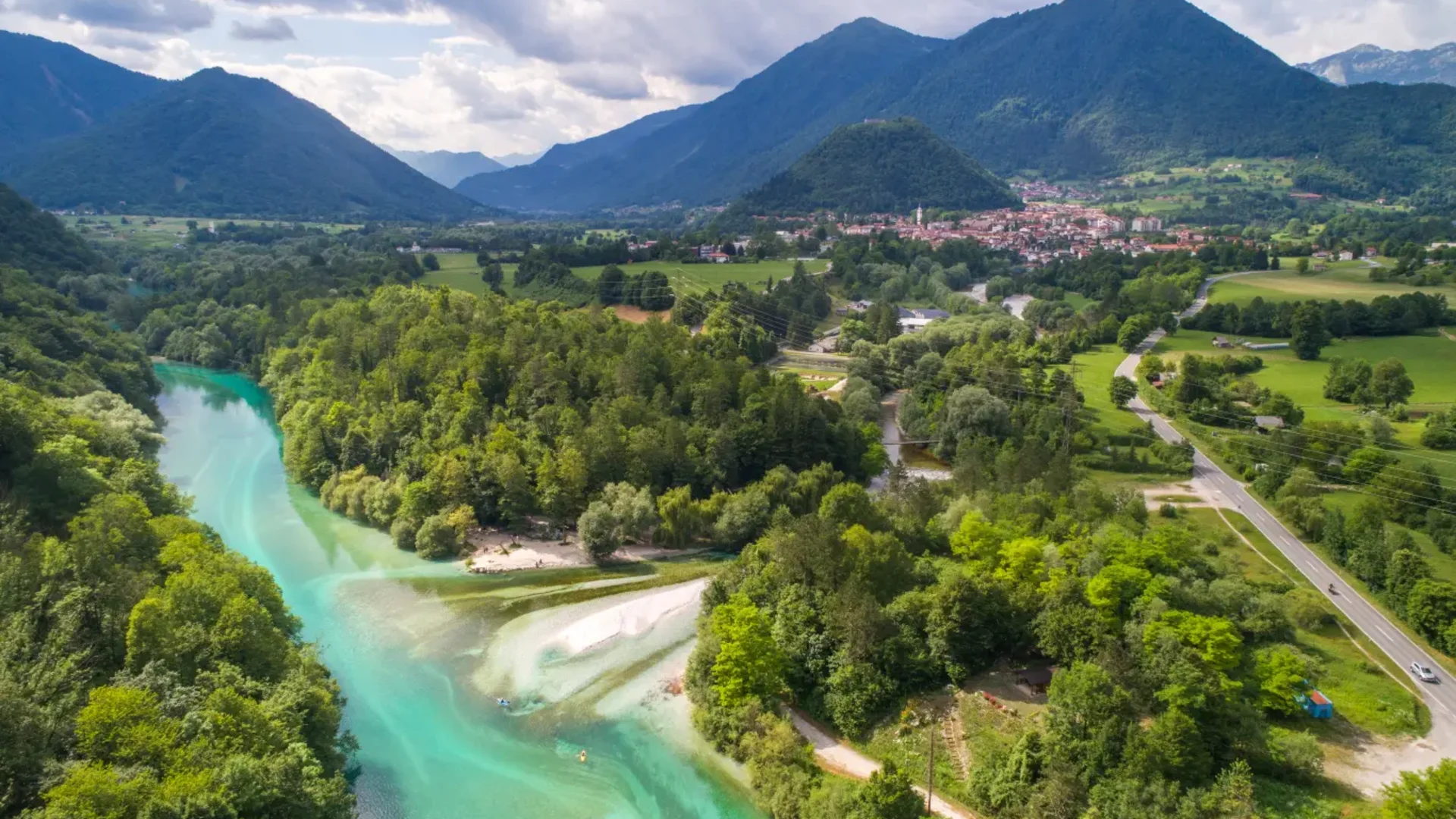 Rivier door groen dal met bergen en dorp op de achtergrond