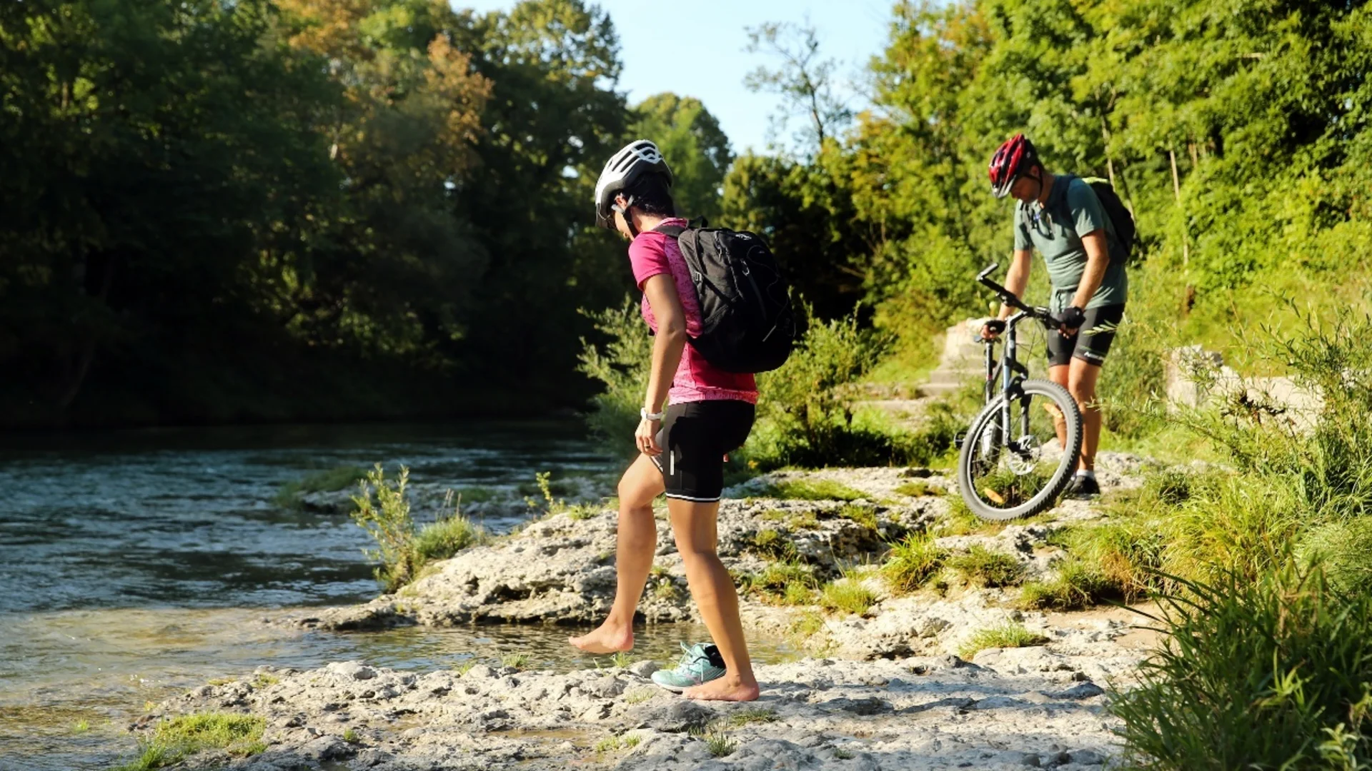 Tour-Detail Zwei Radfahrer mit Helm am Ufer eines Flusses in der Natur
