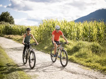 Natz-Schabs Two people riding mountain bikes on a sunny dirt trail