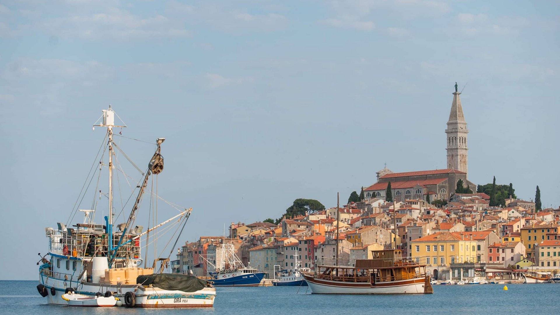 Boats in front of a coastal town with a church on a hill