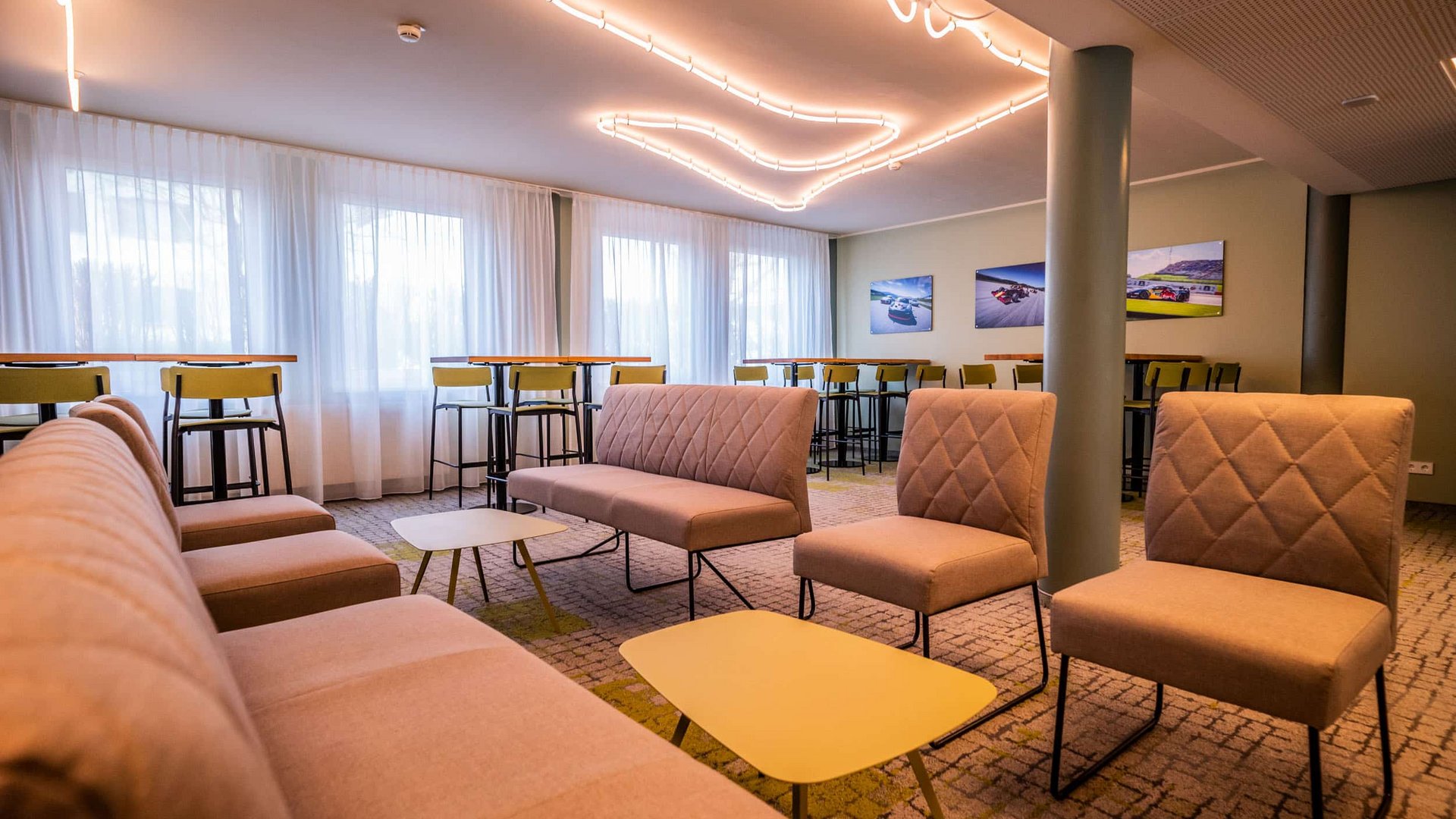 Modern lounge area with beige chairs and high tables in the background