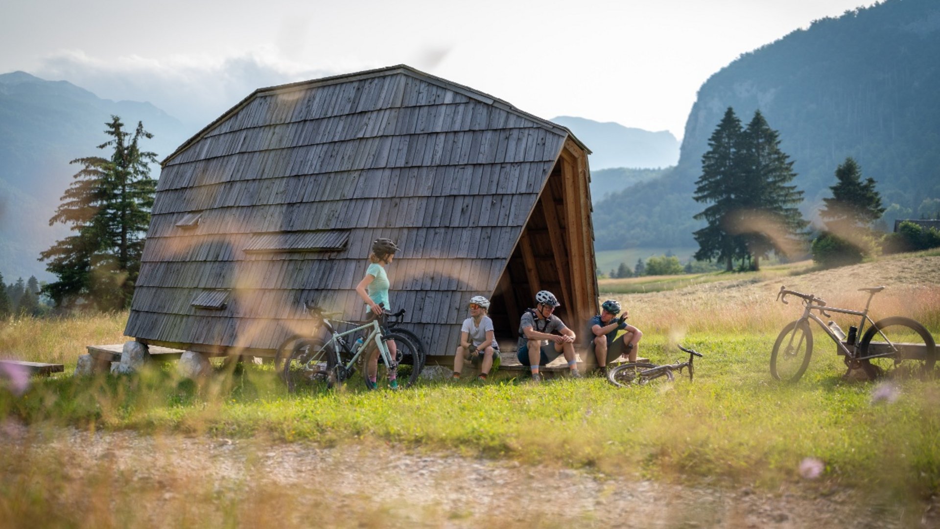 Cyclists resting by wooden shelter in mountain landscape