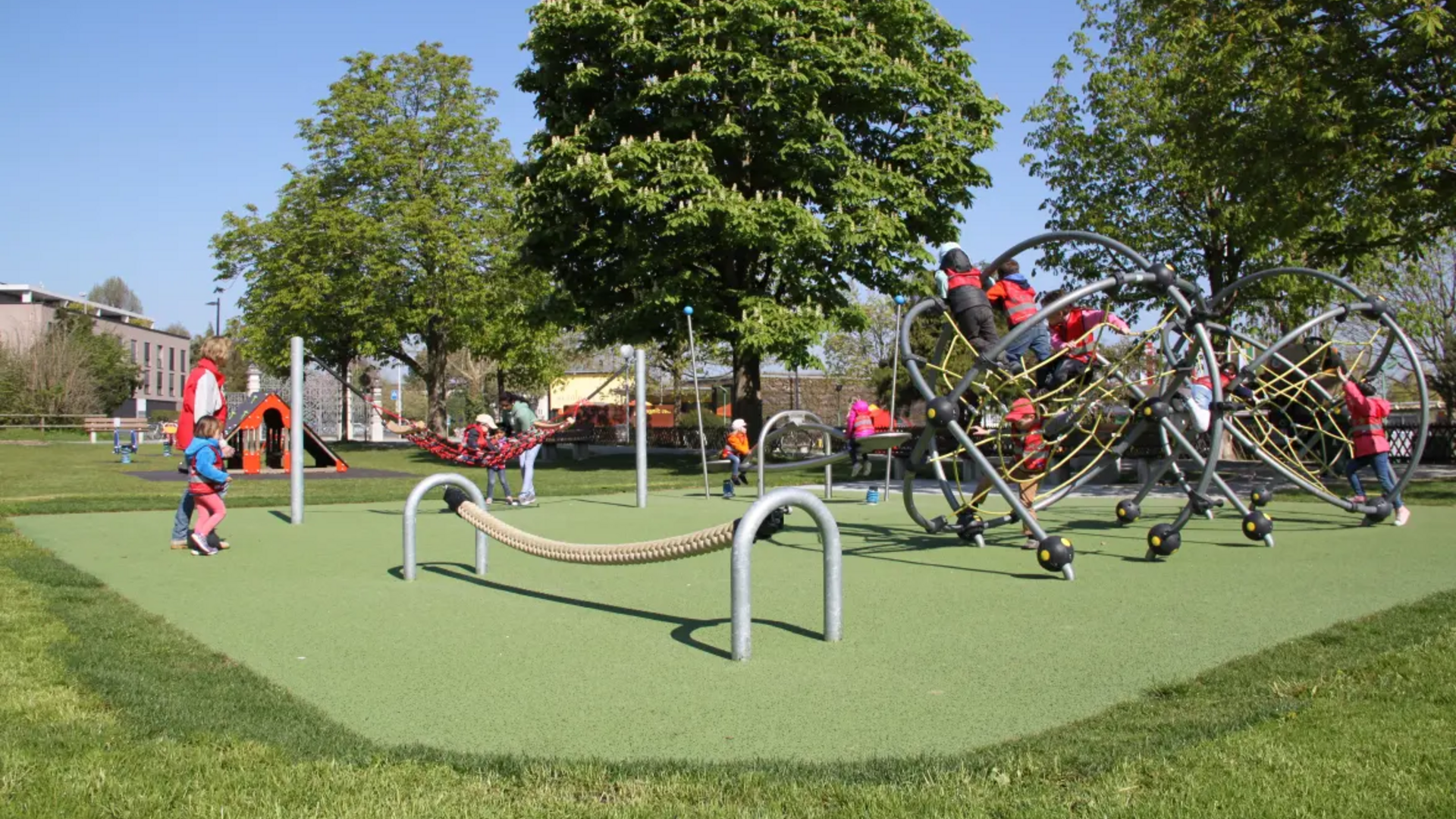 Children playing on a large climbing structure in a sunny park